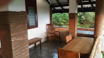 A room with a wooden table and chairs, a bench, and a window with a view of greenery.