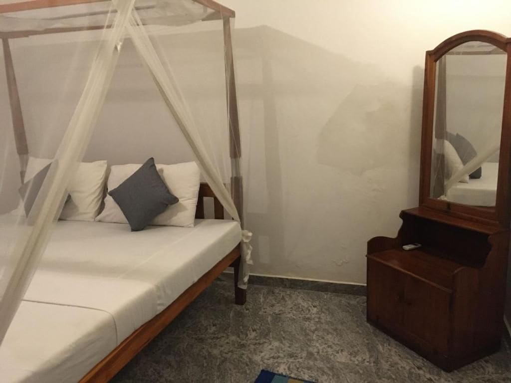 Un dormitorio con una cama con dosel, un aparador de madera y un espejo.
