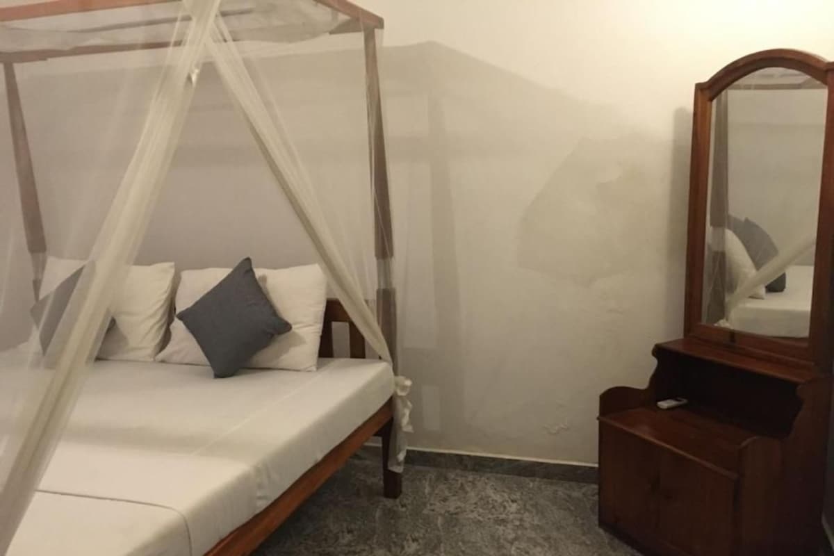 Un dormitori amb un llit amb cortines, un taulell de fusta i un mirall.