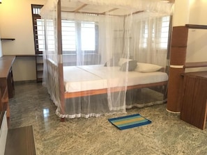 Una habitació amb un llit sota una bugada, una catifa petita i un armari de fusta.