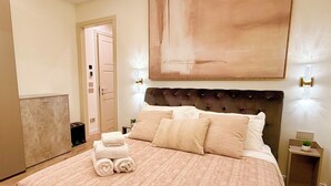 Ein Hotelzimmer mit einem großen Bett, einem Kopfteil, einem Bild an der Wand und einem Nachttisch mit einer Lampe.