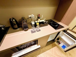 Una cocina con barra de café, hervidor, botella y copa de vino.