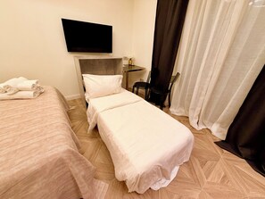 A hotel room with a bed, a chair, a table, a TV, and a window with curtains. - A&V Boutique Apartments | Prestige Suite 10 – 3 guests, downtown Viareggio (Viareggio)