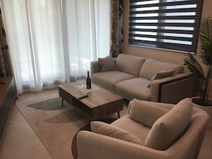 A living room with a sofa, a coffee table, and a remote control. - LOL-HA House, by the sea—a secluded and peaceful spot (Isla Mujeres)