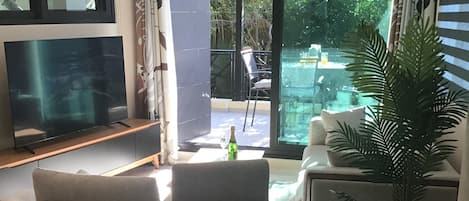 A dining area with a table set for four, a television, and a view of the outdoors.
