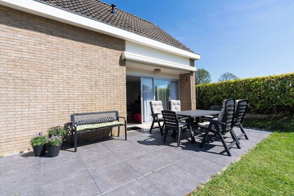 A patio with a table and chairs, a bench, and potted plants.