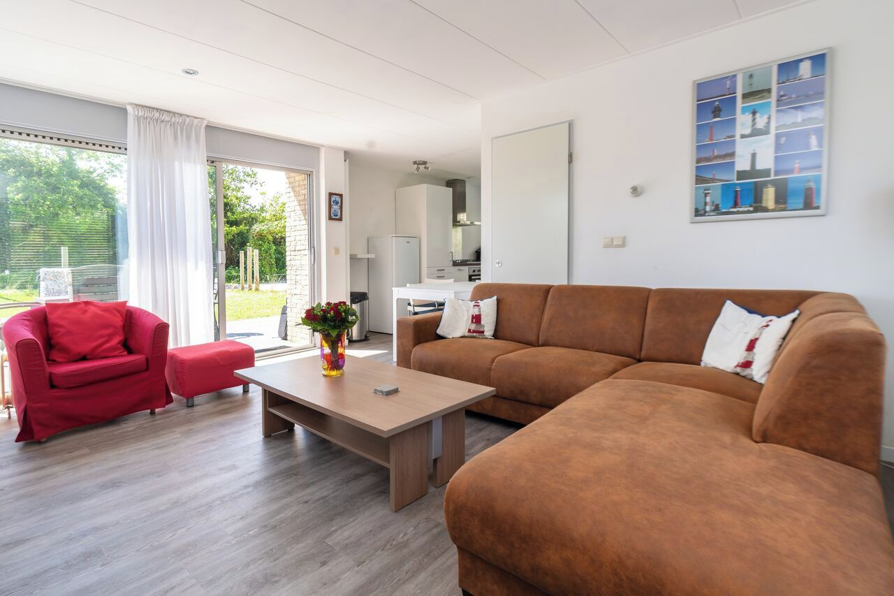 Una sala moderna con un sofá marrón, un sillón rojo y una mesa de centro de madera.
