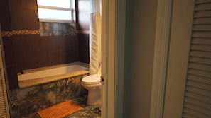 Ein Badezimmer mit Badewanne, Toilette und einem Fenster.