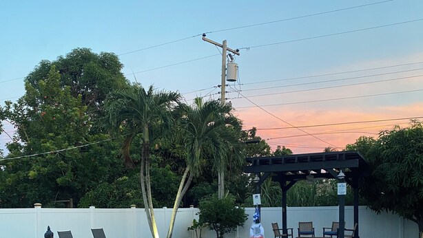Piscina com escada de metal, espreguiçadeiras e área de estar coberta.