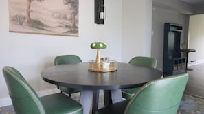 Ein Essbereich mit einem runden Tisch, grünen Sitzmöbeln und einer dekorativen Pilz-Zentralanordnung.