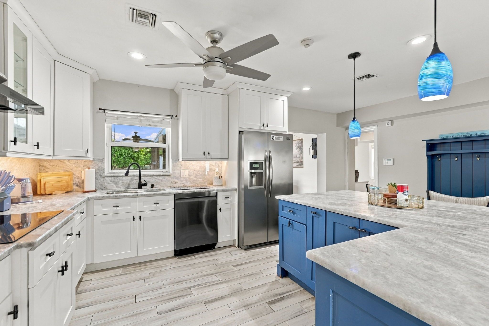 Una cocina moderna con armarios blancos, un refrigerador de acero inoxidable, un lavavajillas y una pared de acento azul.