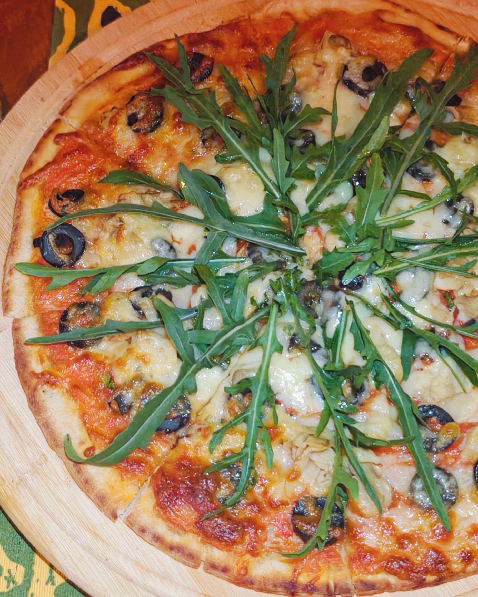 A pizza with toppings and a wooden board.