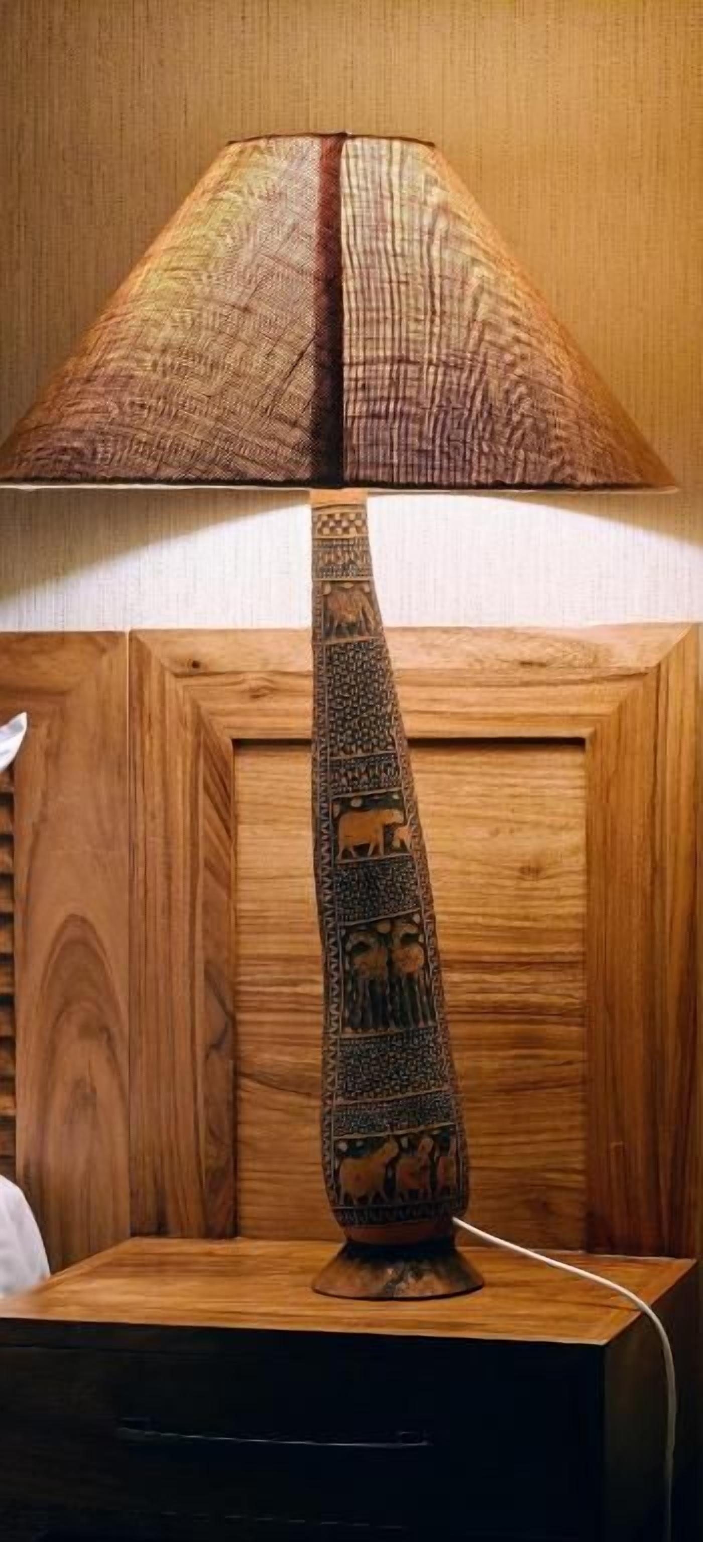 A lamp with a patterned shade and a decorative base on a wooden surface.