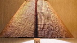Una lámpara con pantalla estampada y base decorativa sobre una superficie de madera.