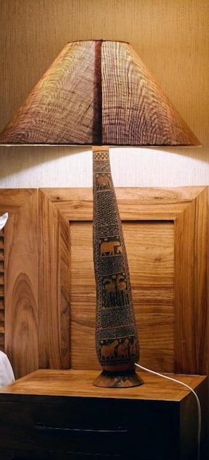 Um abajur com cúpula estampada e base decorativa sobre uma superfície de madeira.