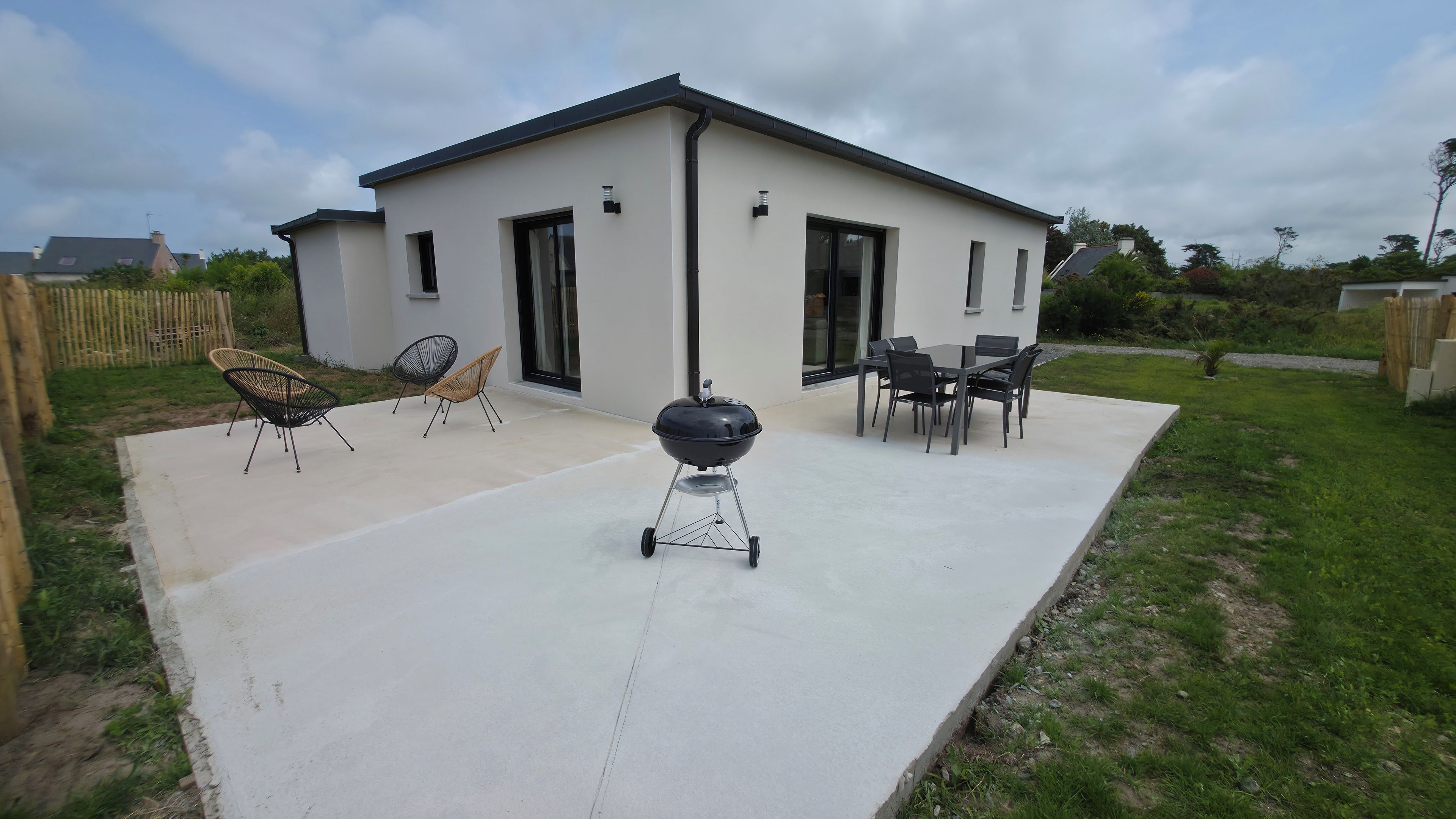 Une maison moderne dotée d’un patio, d’un espace salon extérieur et d’un barbecue.