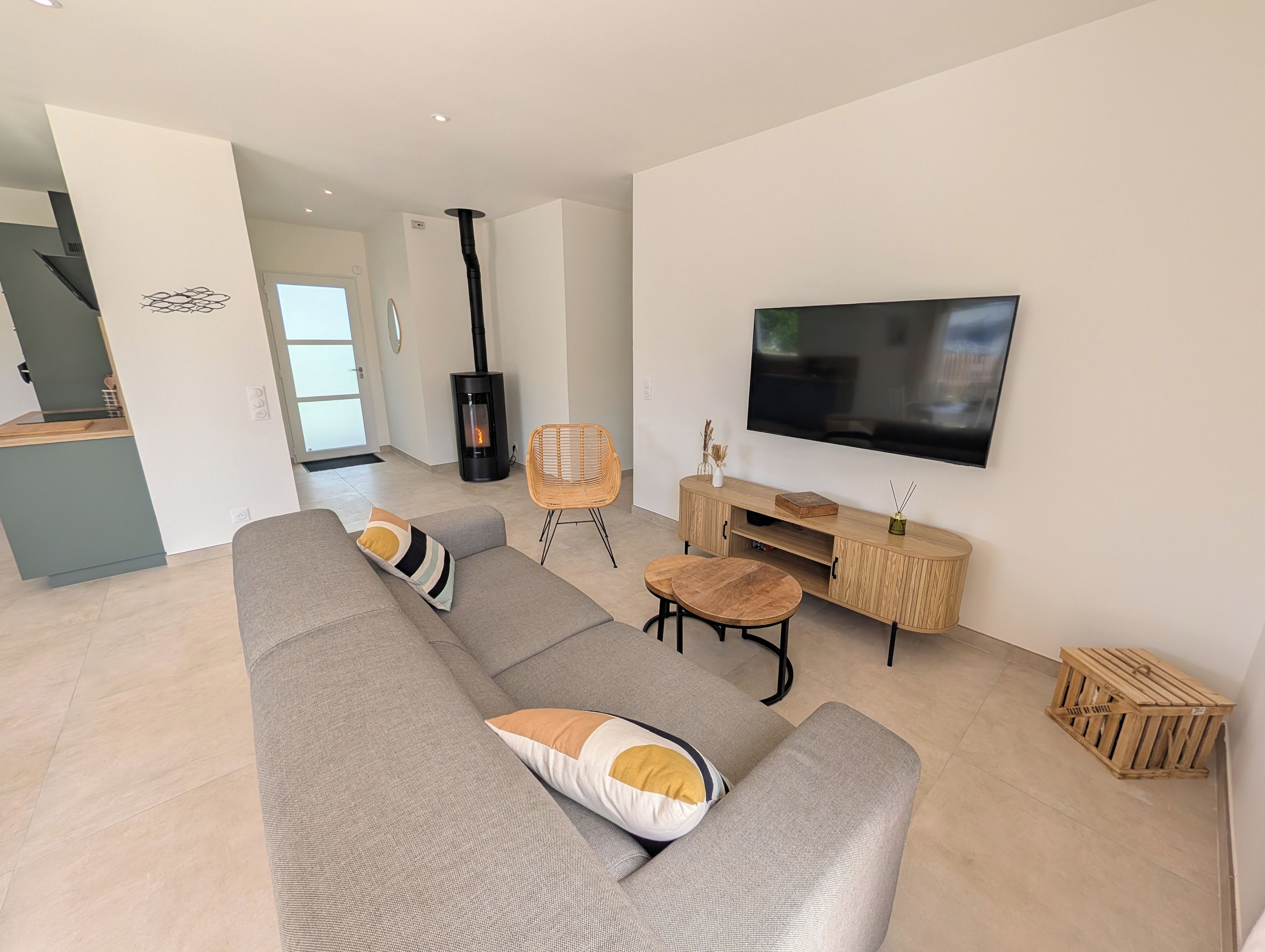 Un salon moderne avec un canapé gris, une table basse en bois, un téléviseur et une cheminée.