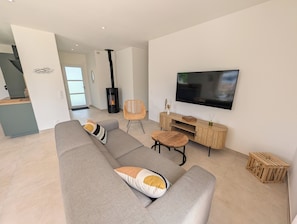 Un salon moderne avec un canapé gris, une table basse en bois, un téléviseur et une cheminée.