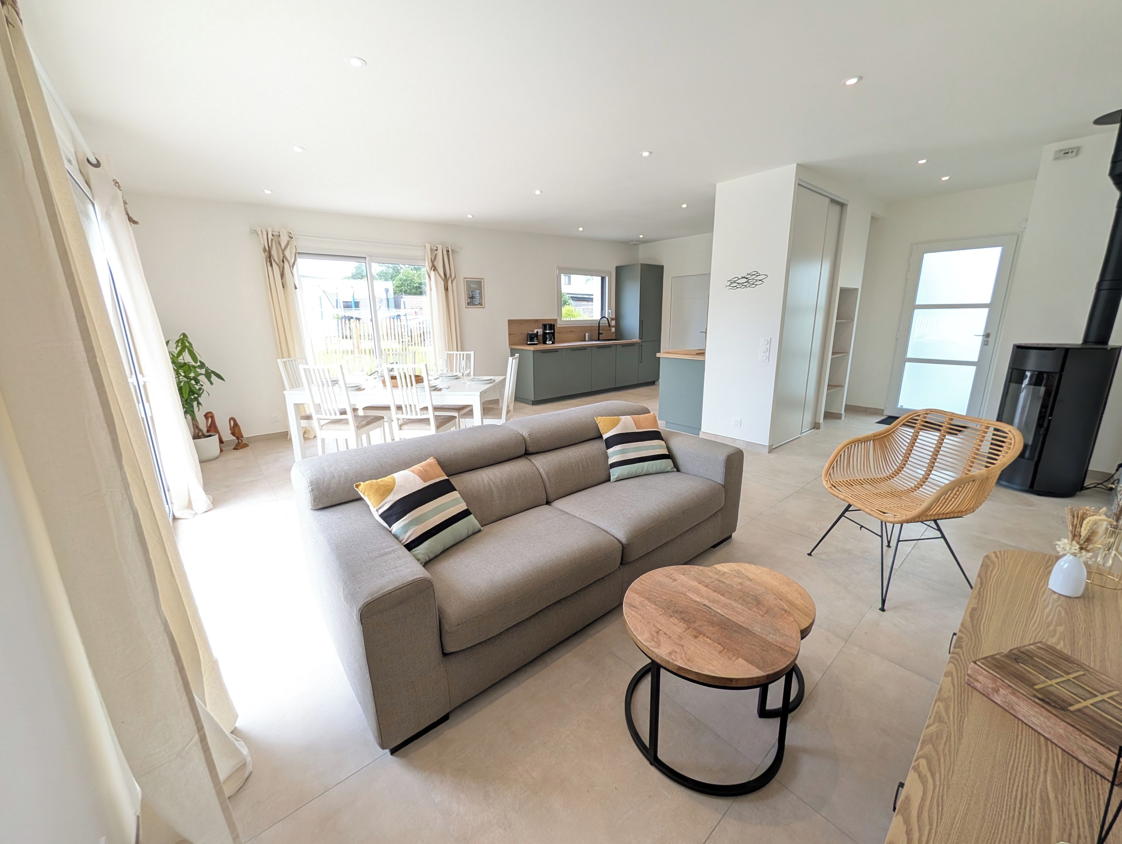 A modern living room with a sofa, a round wooden table, and a wicker chair.