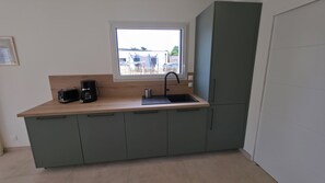 A compact kitchen with a window, a sink, a coffee maker, and a toaster. - Vrbo Property (Le Conquet)