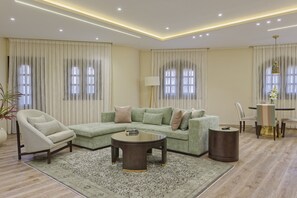 Ein modernes Wohnzimmer mit einer Eckcouch, einem runden Couchtisch und einem Essbereich mit Tisch und Stühlen.