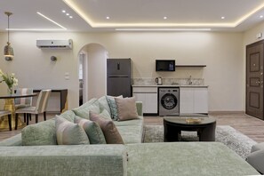 Eine moderne Küche mit Einbauwaschmaschine, ein Essbereich mit Tisch und Stühlen sowie ein Wohnzimmer mit Sofa und Couchtisch.