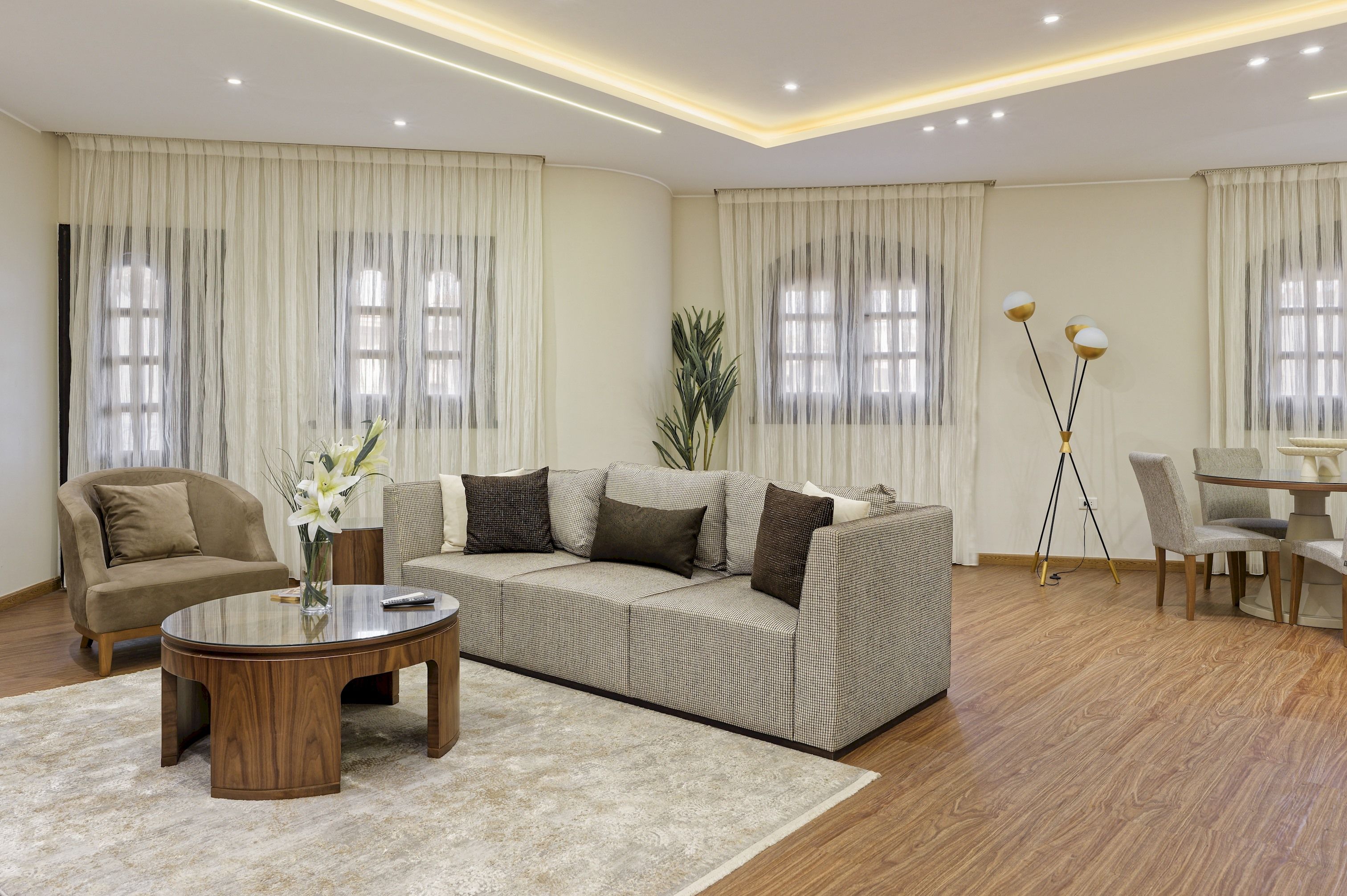 A modern living room with a sectional sofa, a round coffee table, and a dining area with a table and chairs.