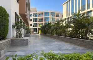 A modern building with a curved facade, multiple balconies, and a landscaped courtyard with palm trees. - Luxury APT - 2BR - La Mirada (IV) (New Cairo City)
