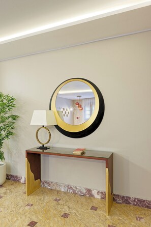 A room with a round mirror on a wall, a desk with a lamp, and a potted plant. - Luxury APT - 2BR - South Teseen (I) (New Cairo City)