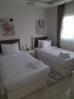 Habitación de hotel con dos camas, una mesita de noche, una lámpara y obras de arte en las paredes.