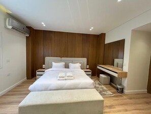 Ett modernt sovrum med en stor säng, sängbord, ett skrivbord och en luftkonditioneringsanläggning.
