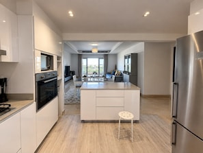 A modern kitchen with a central island, stainless steel appliances, and a view to a balcony. - VESTA - Luxury Apt- 3br - cfc (xlvii) (New Cairo City)