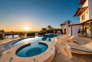 Ein Poolbereich mit Liegestühlen und Blick auf den Sonnenuntergang.