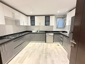 A modern kitchen with grey cabinets, a black countertop, and a wooden floor. - VESTA - Luxury Apt- 3br - cfc (xlviii) (New Cairo City)