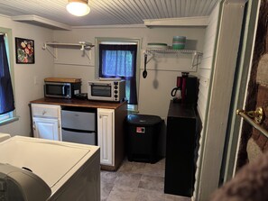 Pieni, käytännöllinen keittiönurkkaus, jossa on mikroaaltouuni, leivänpaahdin ja kahvinkeitin hyllyllä.