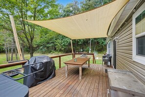 A wooden deck with a table and chairs, a barbecue grill, and a shade sail. - Chase Cabin-Wi-Fi, Hot Tub, Game Room, Firepit (Chase)