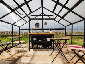 Een geodetische koepelstructuur met een centrale tafel, banken en uitzicht op het landschap.