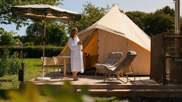 A tent with a covered outdoor seating area, a table, and a chair.