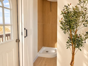 Un baño con piso de madera, una bañera blanca y una pared de madera.