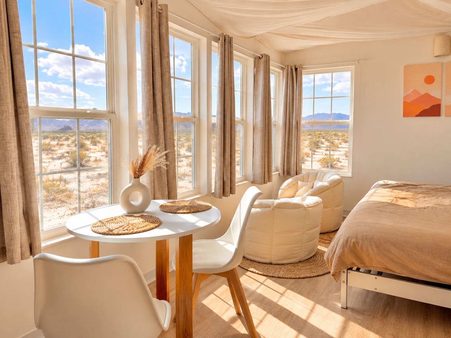 A room with a bed, a round table with chairs, and large windows with curtains.