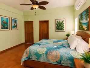 A bedroom with a bed, a ceiling fan, and wall art. - Villa Terrapin Station in Hopkins, Beachfront, Private Pool + Rooftop Tiki Bar (Hopkins)