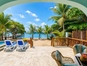 A beachside patio with lounge chairs, a wooden fence, and a view of the ocean. - Villa Terrapin Station in Hopkins, Beachfront, Private Pool + Rooftop Tiki Bar (Hopkins)