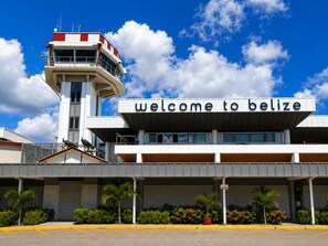 A modern building with a sign that reads 'welcome to belize' and a control tower in the background. - Villa Terrapin Station in Hopkins, Beachfront, Private Pool + Rooftop Tiki Bar (Hopkins)