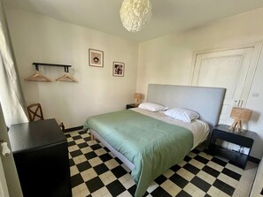 A bedroom with a checkered floor, a bed with a grey headboard, two wall-mounted light fixtures, and a door. - Large house in Mulsanne - 10 guests (Mulsanne)