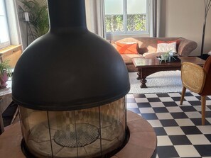 A modern living room with a large, round, glass-enclosed wood-burning stove, a checkered floor, and a sofa with cushions. - Large house in Mulsanne - 10 guests (Mulsanne)