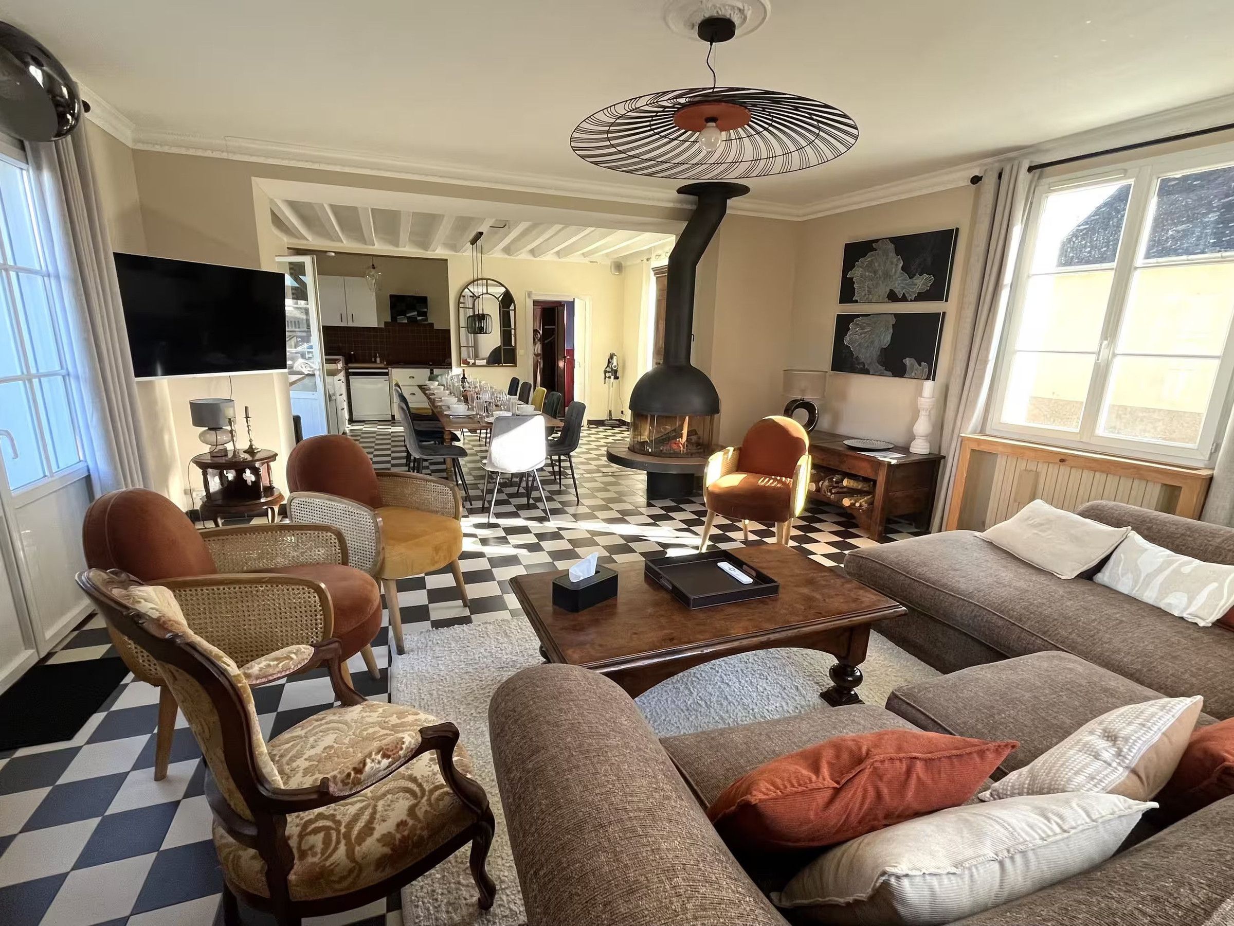 Un salon avec un sol à carreaux, un canapé, des fauteuils, une table basse et une cheminée.