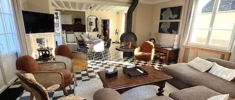 A living room with a checkered floor, a sofa, armchairs, a coffee table, and a fireplace.