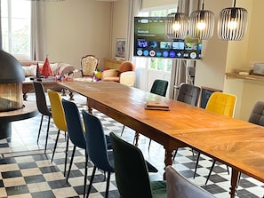 A dining area with a long wooden table, multiple chairs, a television screen, and a fireplace. - Large house in Mulsanne - 10 guests (Mulsanne)