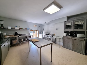 A kitchen with stainless steel appliances, a central island, and a decorative cabinet with glass doors. - Cottage, pets allowed - 11 guests (Saint-Paul-d'Uzore)