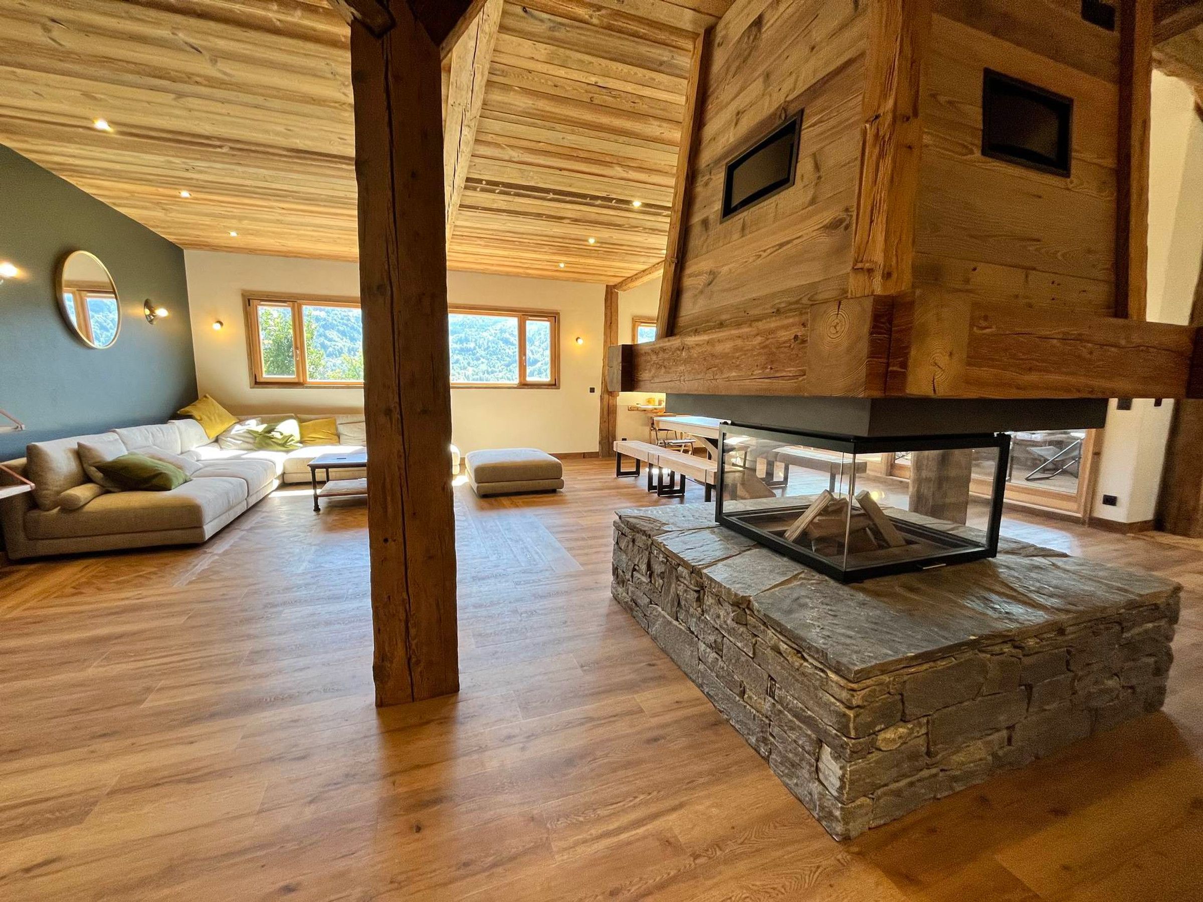 A spacious living area with a stone fireplace, wooden beams, and a modern sofa.